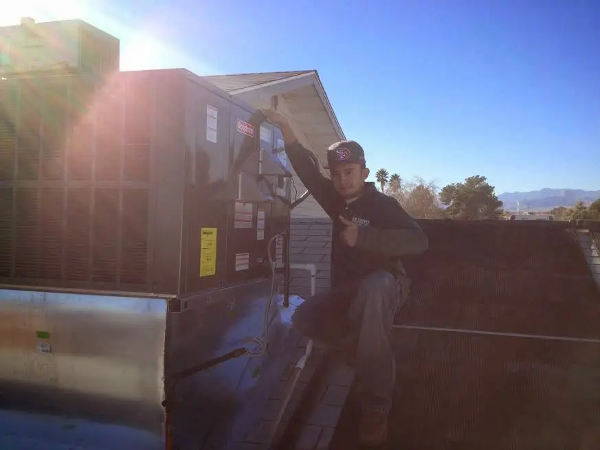 HVAC technician performing AC Tune-Up on a rooftop unit in Pell City